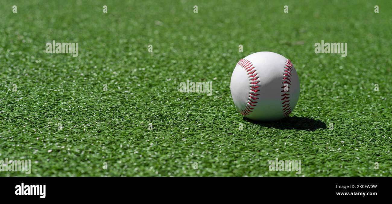 Baseball ball on green grass field. Sport theme background. Horizontal sport theme poster, greeting cards, headers, website and app Stock Photo