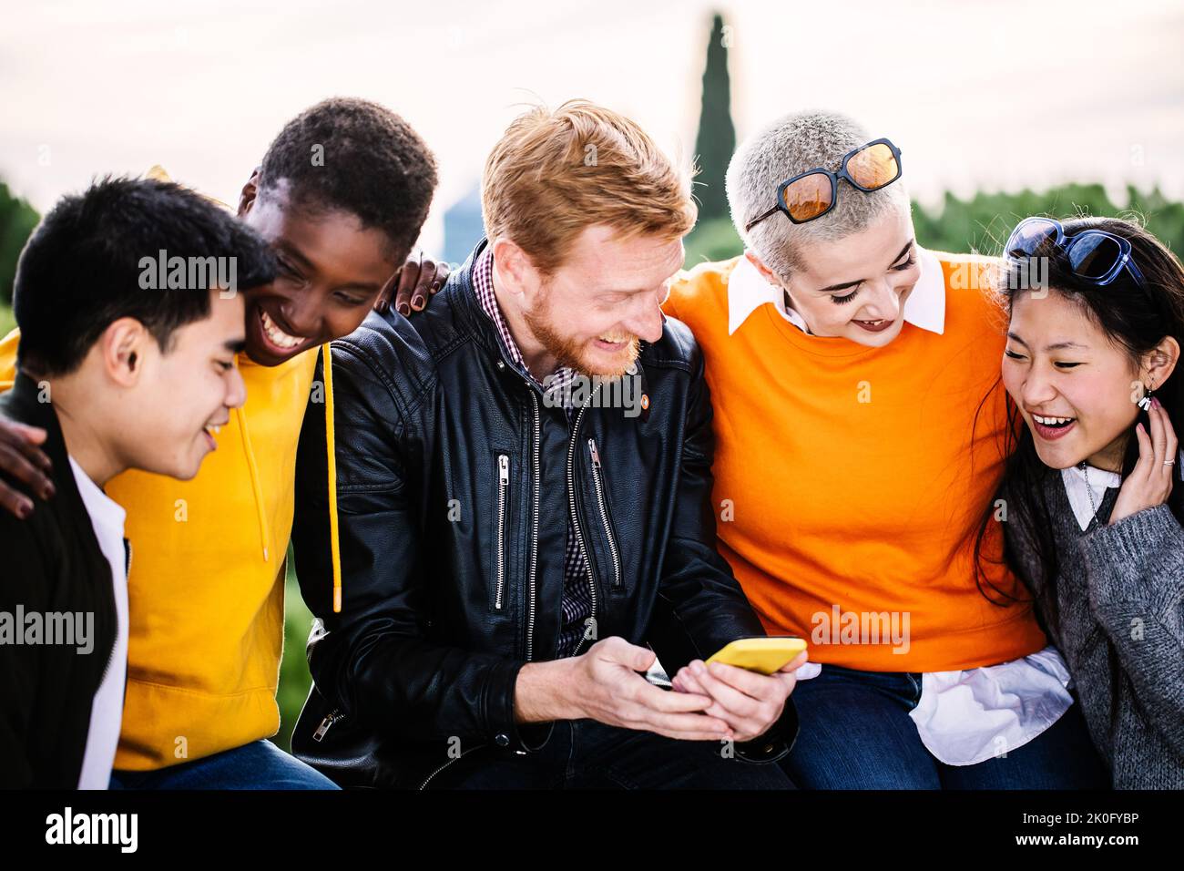 Happy young group of student friends having fun together using mobile phone Stock Photo