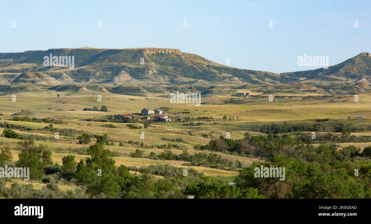 Evening light on a rural landscape with buttes and ranch or farm