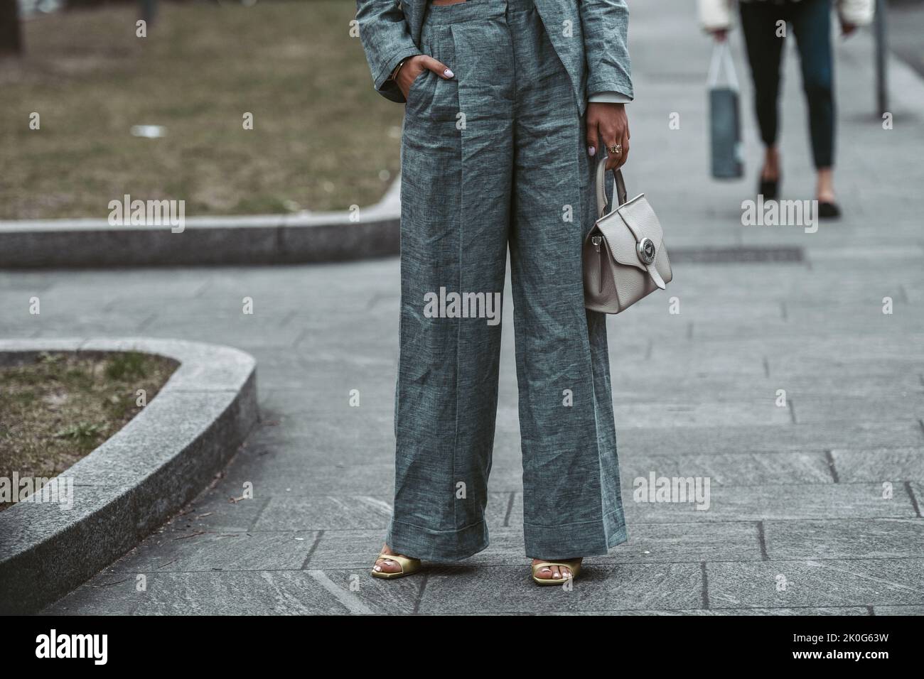 Milan, Italy - February, 24: Street style, woman wearing white cropped shirt, a gray blazer jacket, gray matching suit pants, a beige leather handbag Stock Photo