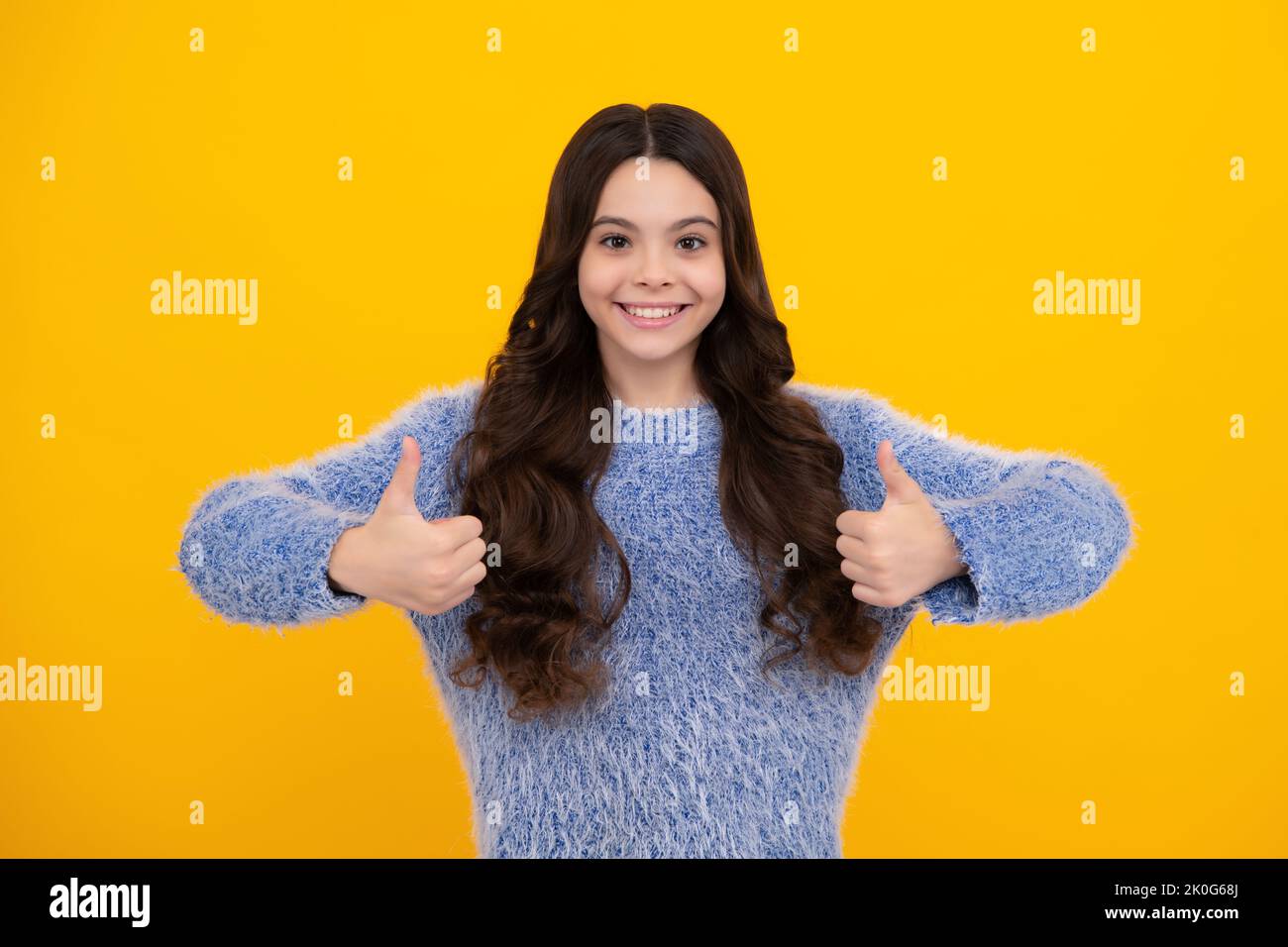 Happy teenager, positive and smiling emotions of teen girl. Happy casual teenager child girl showing thumb up and smiling isolated on yellow Stock Photo