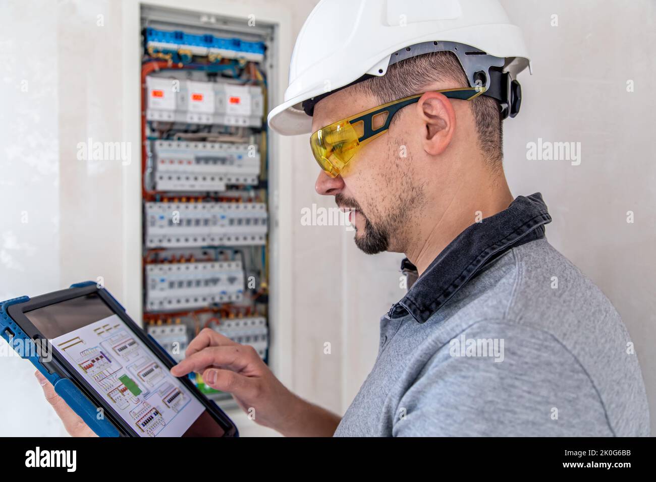 Electrical technician looking focused while working in a switchboard with fuses. Stock Photo