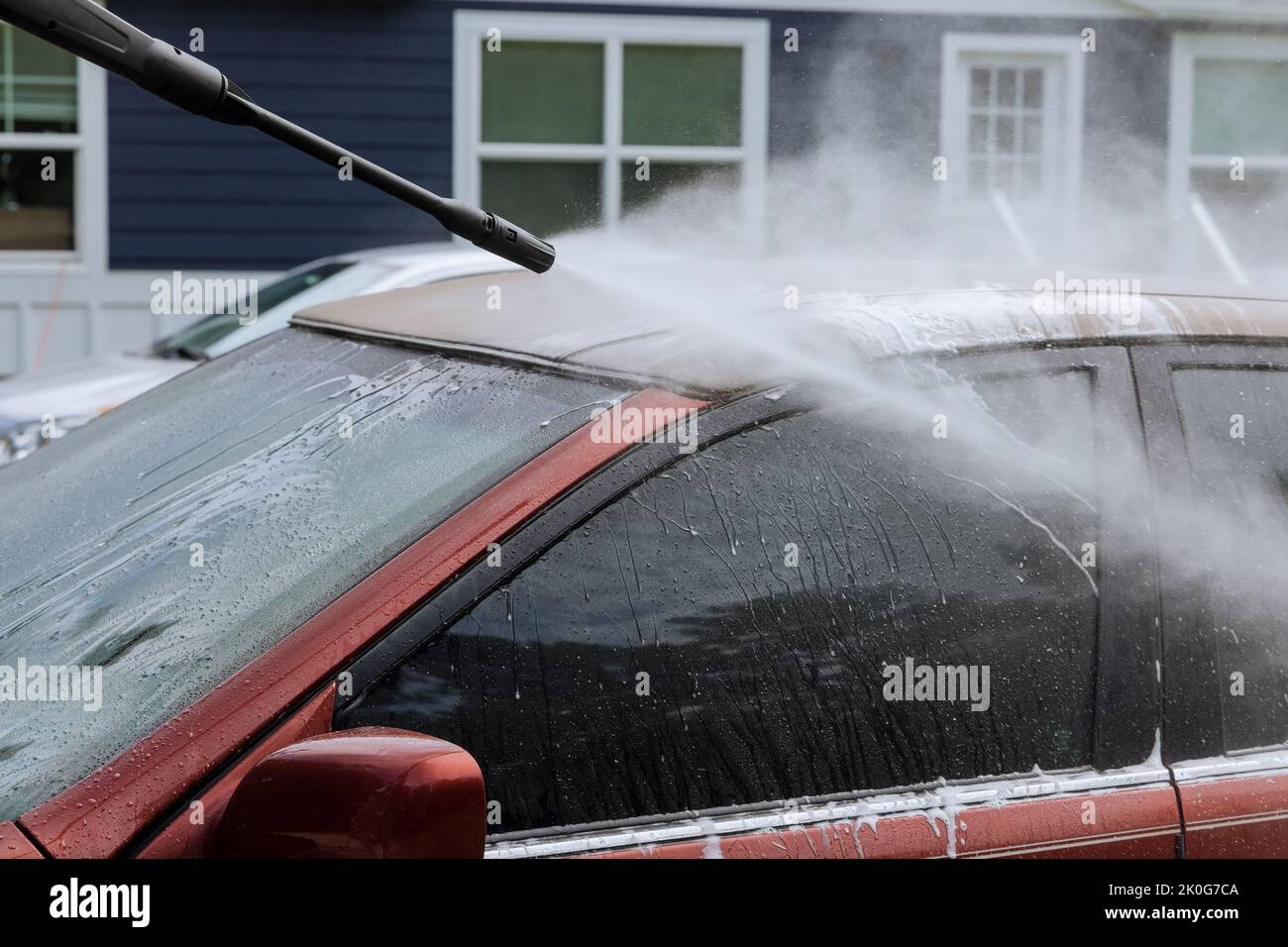 During the washing of a car, a man sprays water with high pressure jets to clean the vehicle Stock Photo