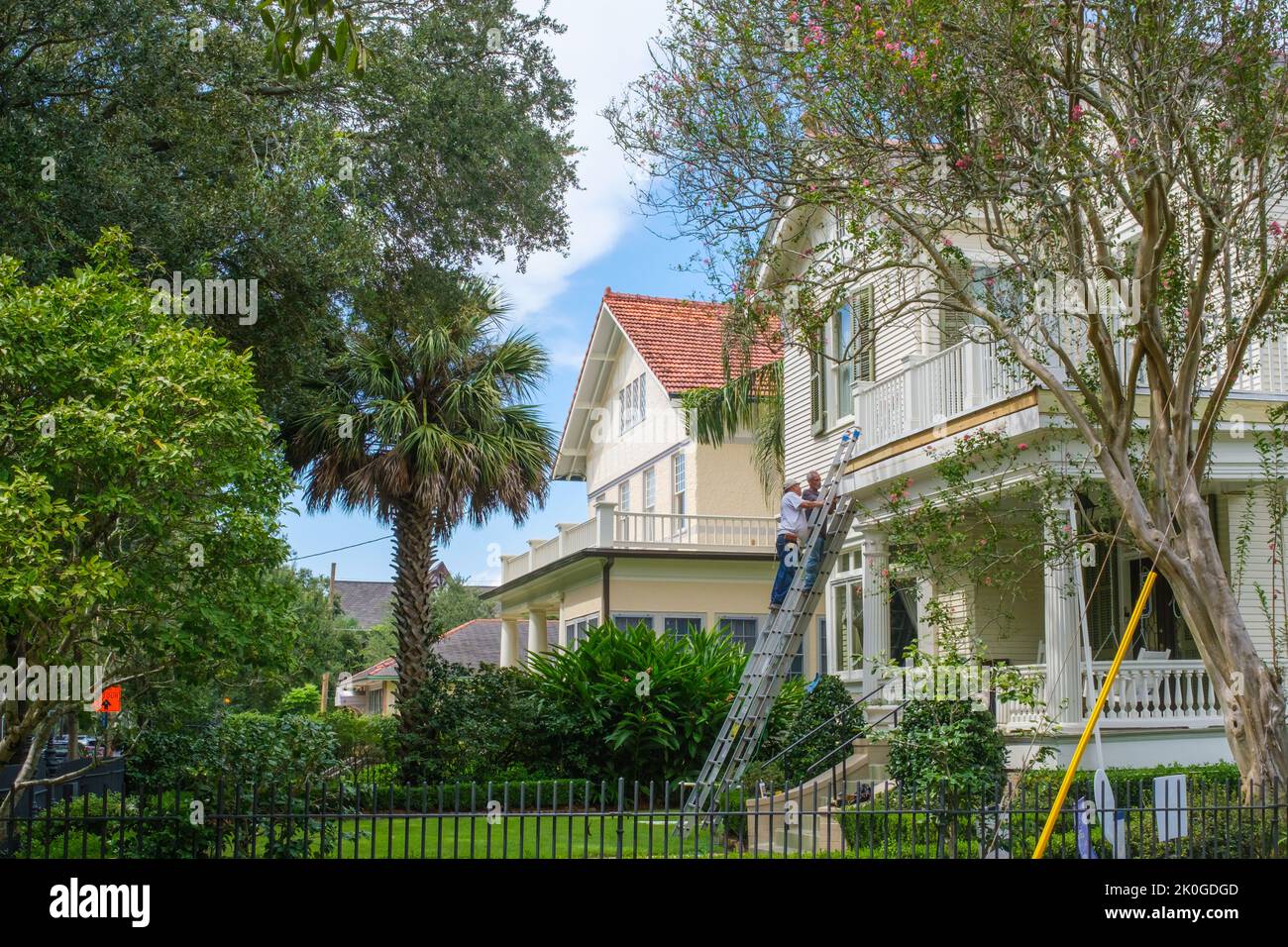 NEW ORLEANS, LA, USA  - SEPTEMBER 7, 2022: Two workers on ladders repairing an historic house on St. Charles Avenue in Uptown neighborhood Stock Photo