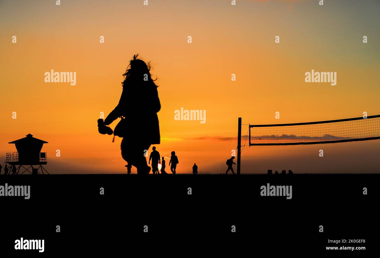 Silhouettes of people on a beach at sunset Stock Photo