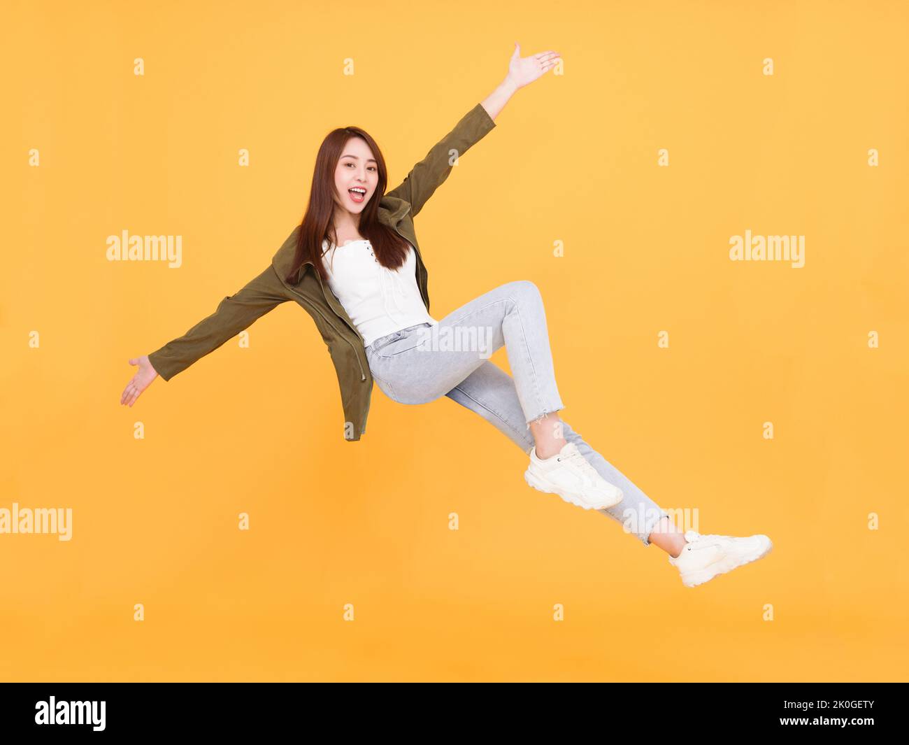 Happy  young woman  jumping and dancing  isolated over yellow background Stock Photo