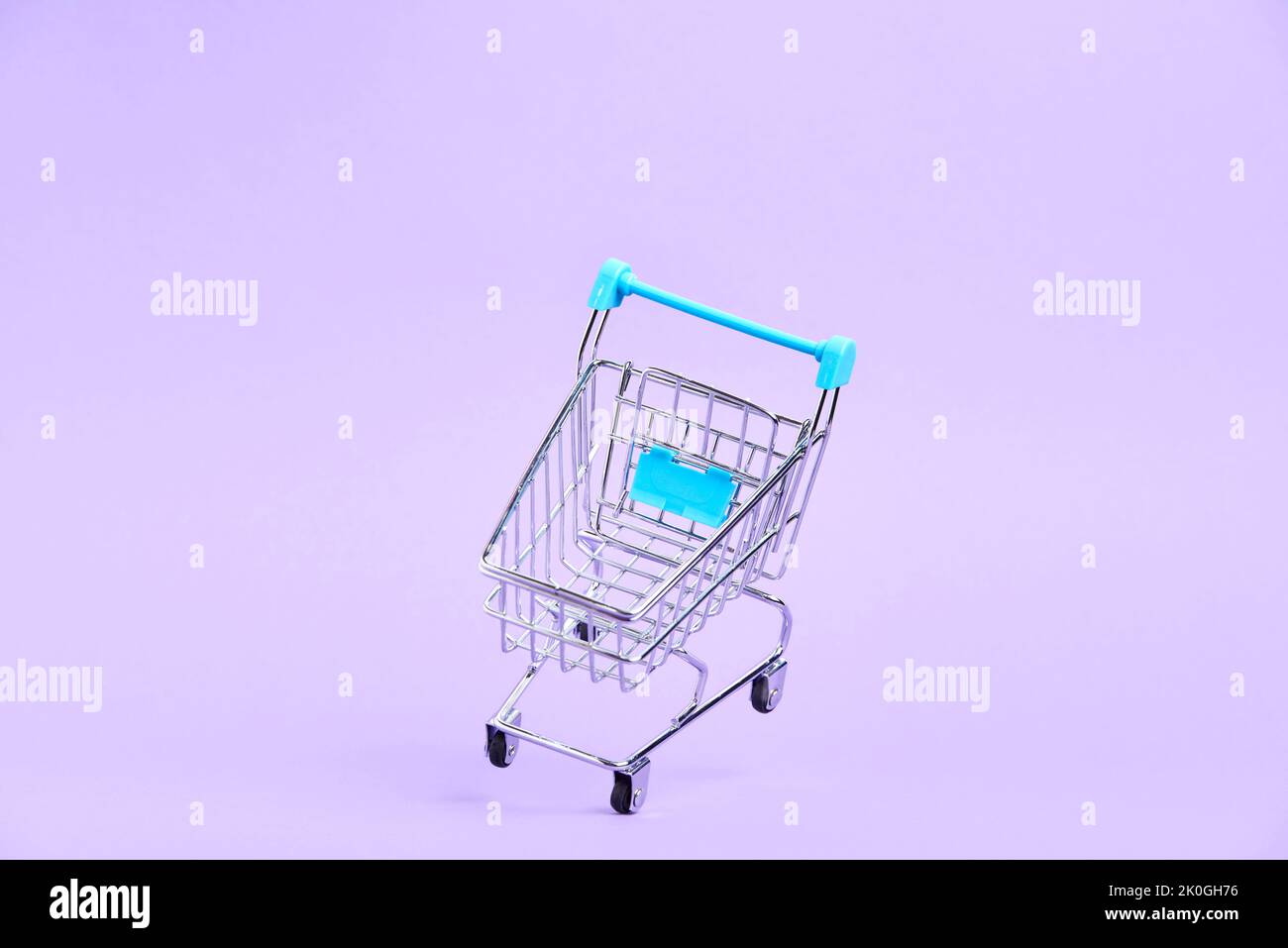Empty shopping cart with light blue details floating on a pastel lilac background. Minimalist design with copy space. Concepts: market deals, seasonal Stock Photo