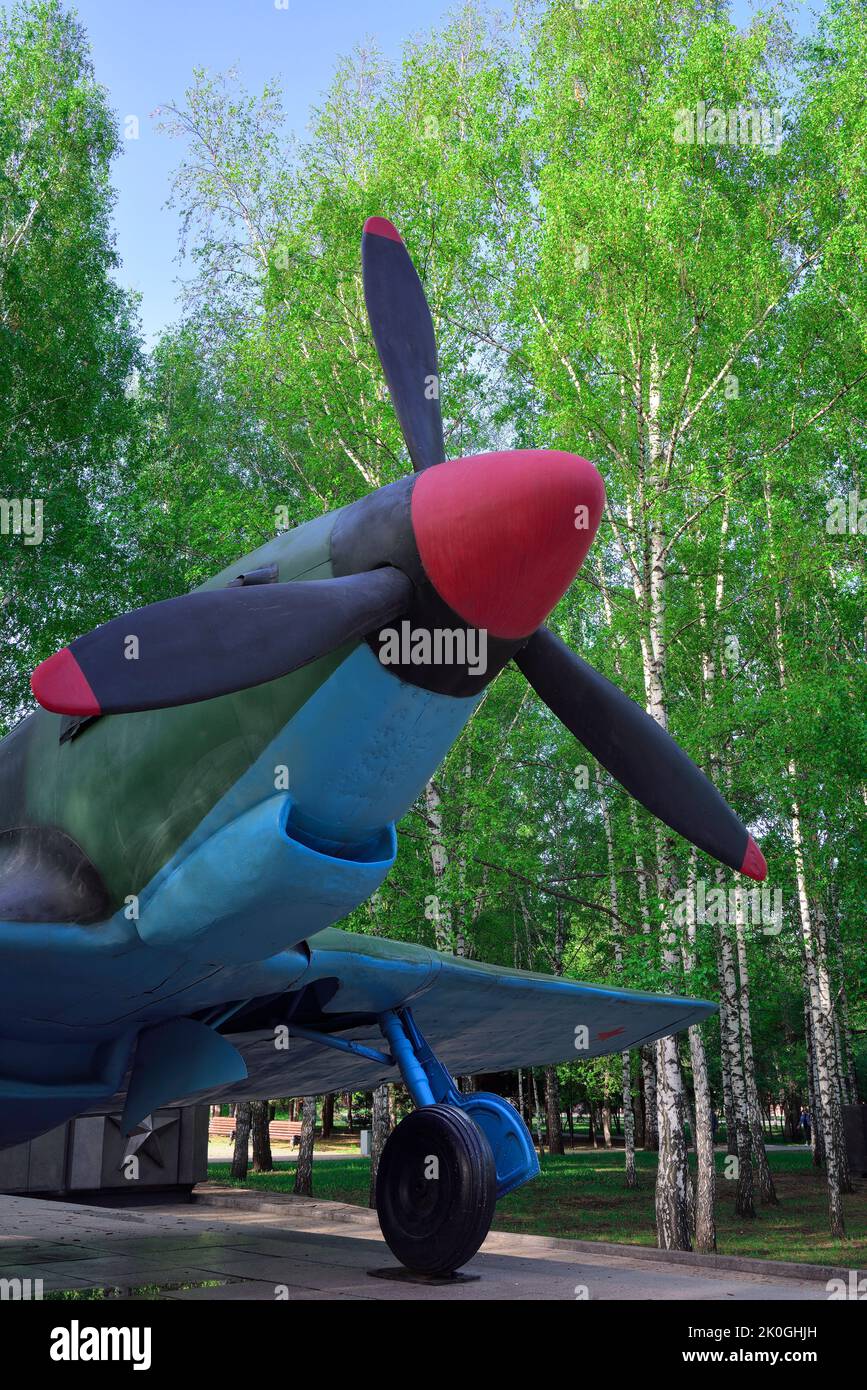 Monument to the plane in the park. World War II aircraft among spring