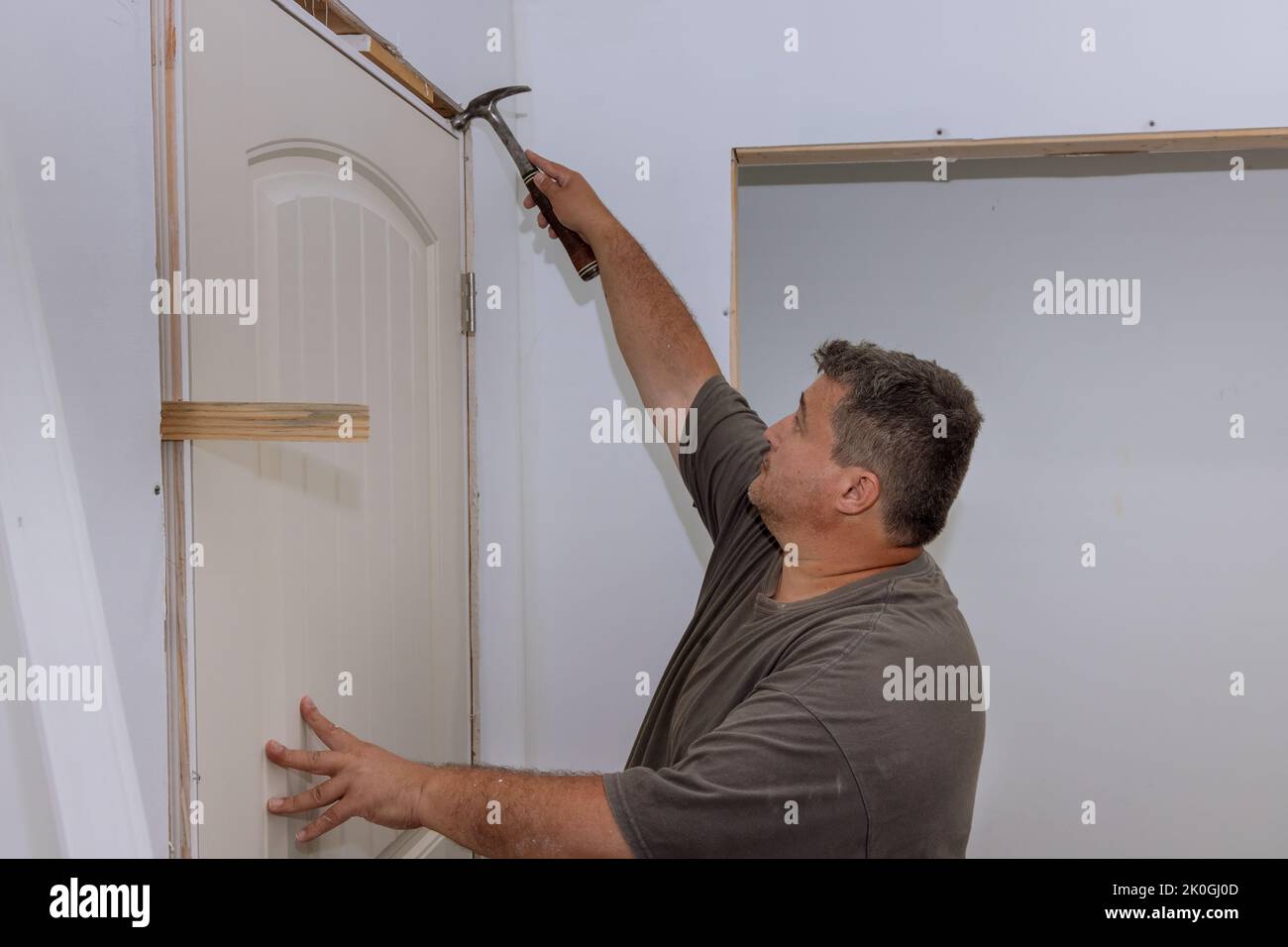 A trim worker uses a hammer when installing interior doors in a new