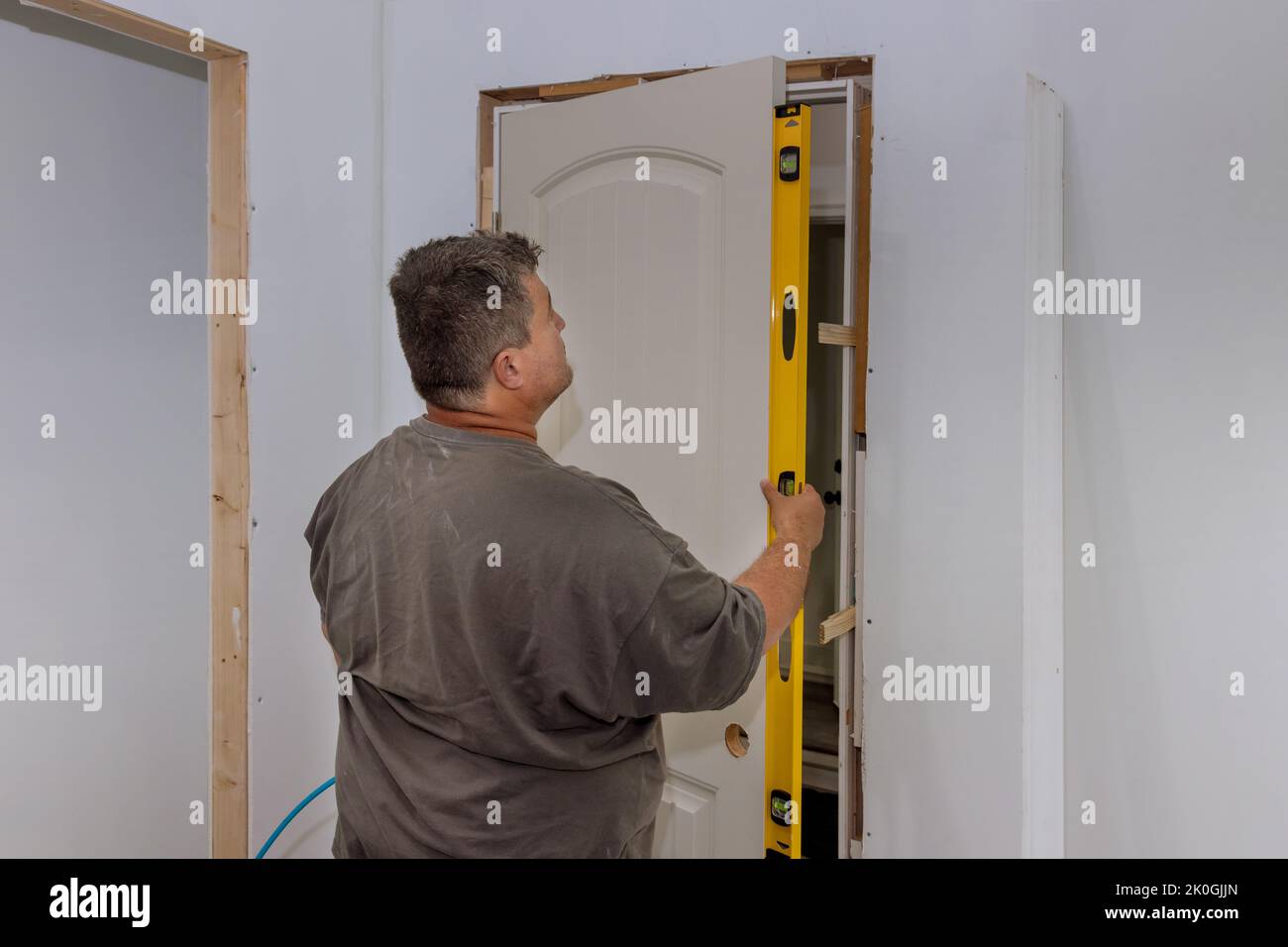 An employee leveling the interior doors of a new house during the installation of the doors is checking whether the correct installation door is being Stock Photo