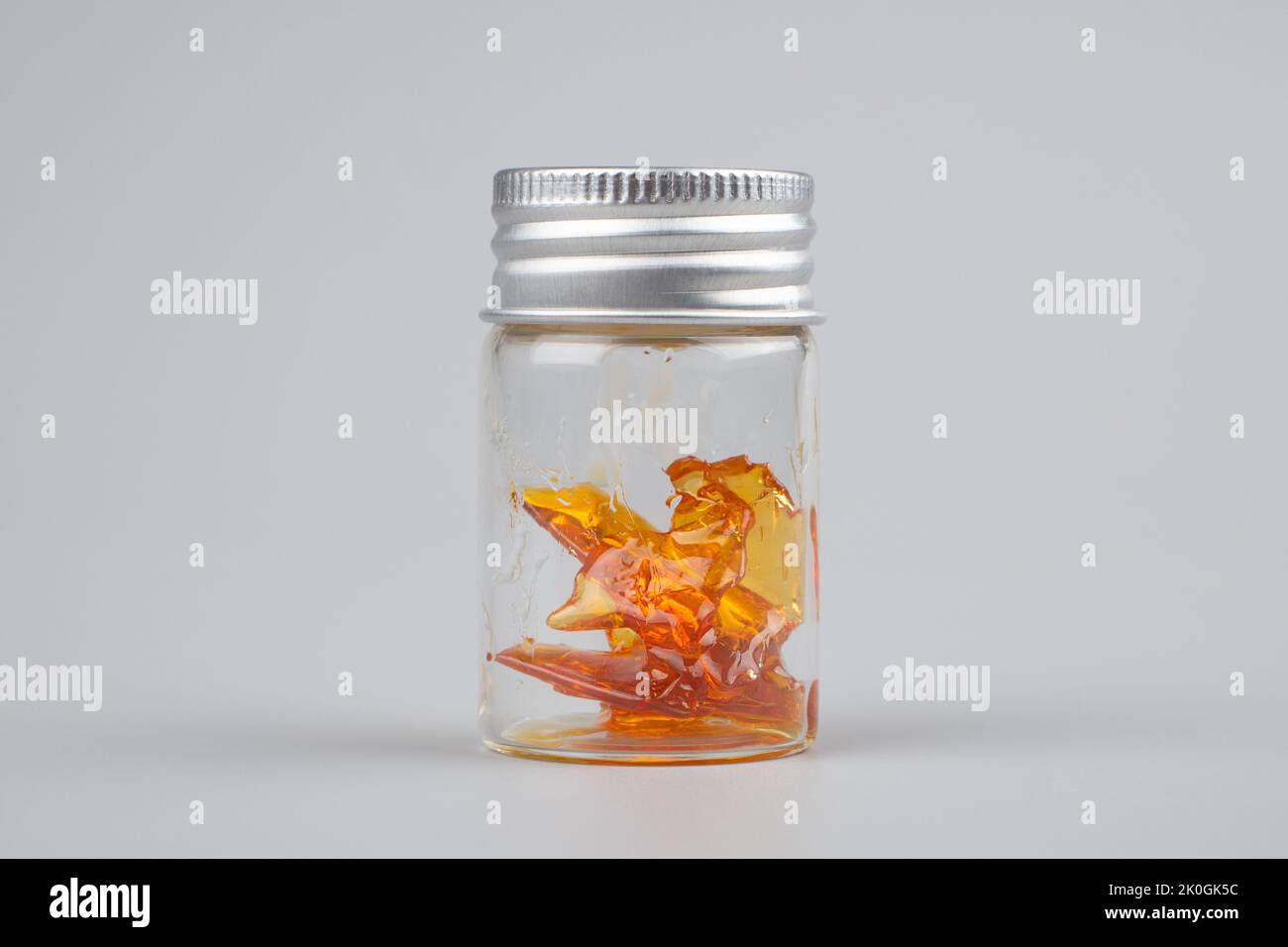 bottle with golden cannabis  extract wax closeup on gray background. Stock Photo