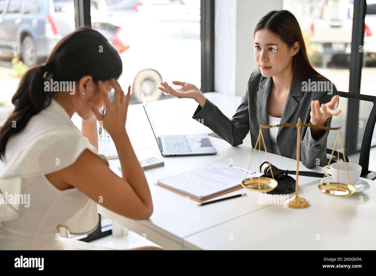 Serious and stressed Asian female client meets with her personal lawyer to discuss and finalize the plan for her lawsuit. Stock Photo