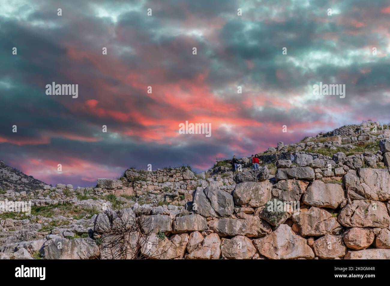018 01 05  Myceane Greece - Tourists climb the ancient walls that myth claims were built by giants under firey sunset sky -  Archelogical finds here p Stock Photo