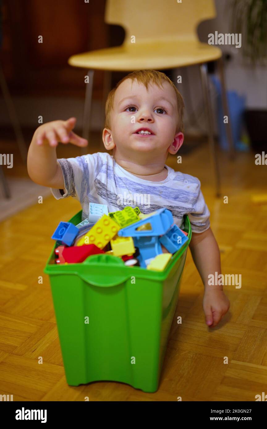 Cute little boy sitting in the plastic box and playing with blocks set Stock Photo