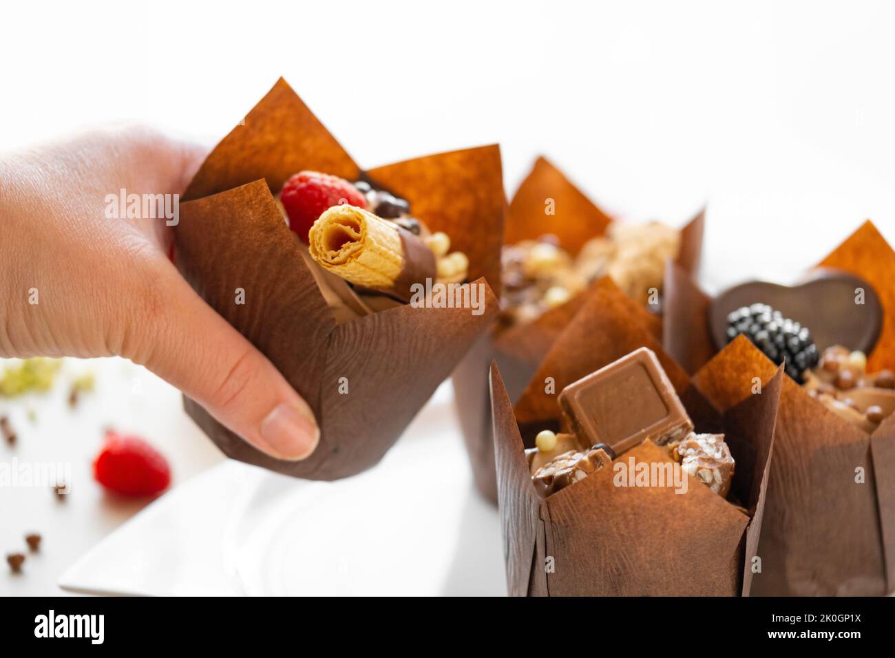 Appetizing muffin in hand on the table with sweets and pastries.Chocolate dessert. Assorted sweet table.Sweets and desserts. Baked goods and desserts Stock Photo
