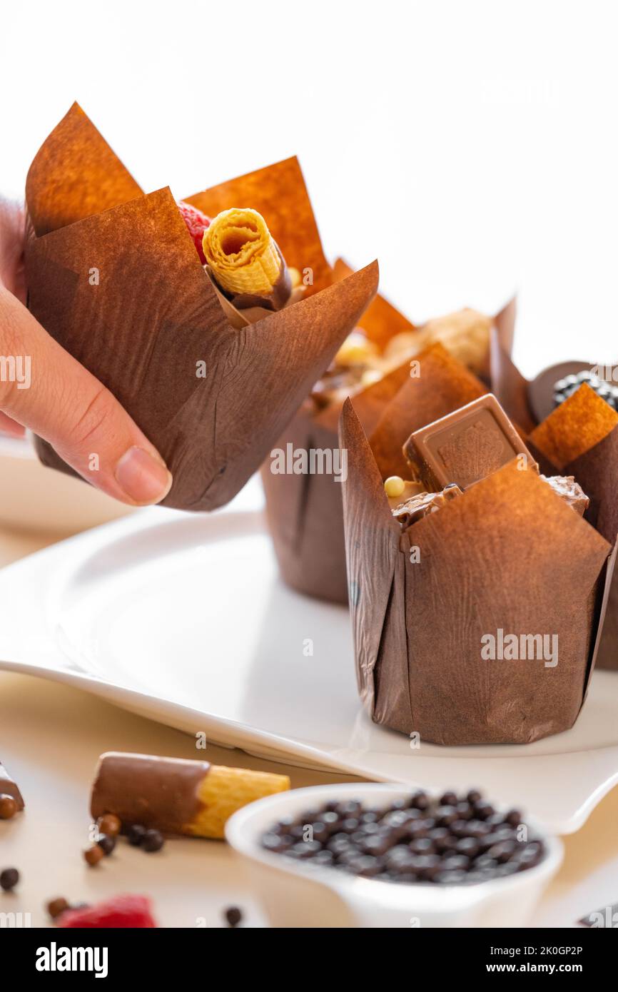 Chocolate cupcake in hand on the table with sweets and pastries.Chocolate dessert. Assorted sweet table.Sweets and desserts. Baked goods and desserts Stock Photo