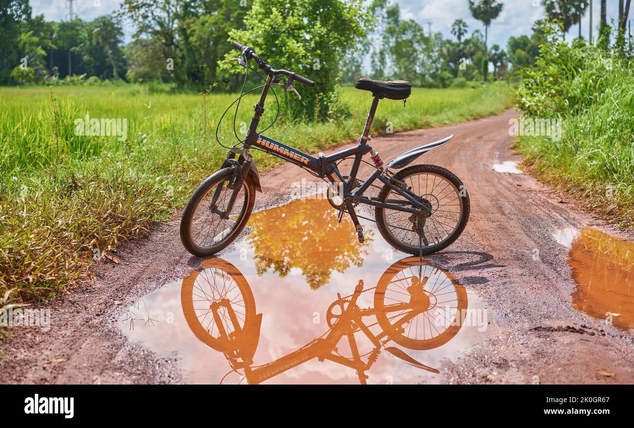 A mountain bicycle and reflection in a puddle of water on a country road. Stock Photo
