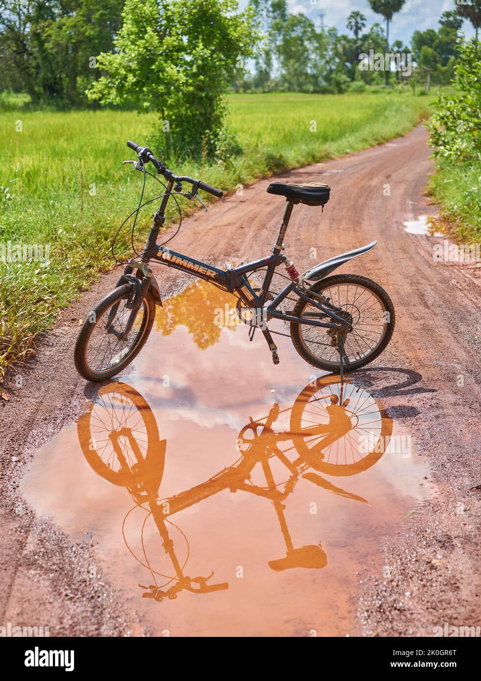 A mountain bicycle and reflection in a puddle of water on a country road. Stock Photo