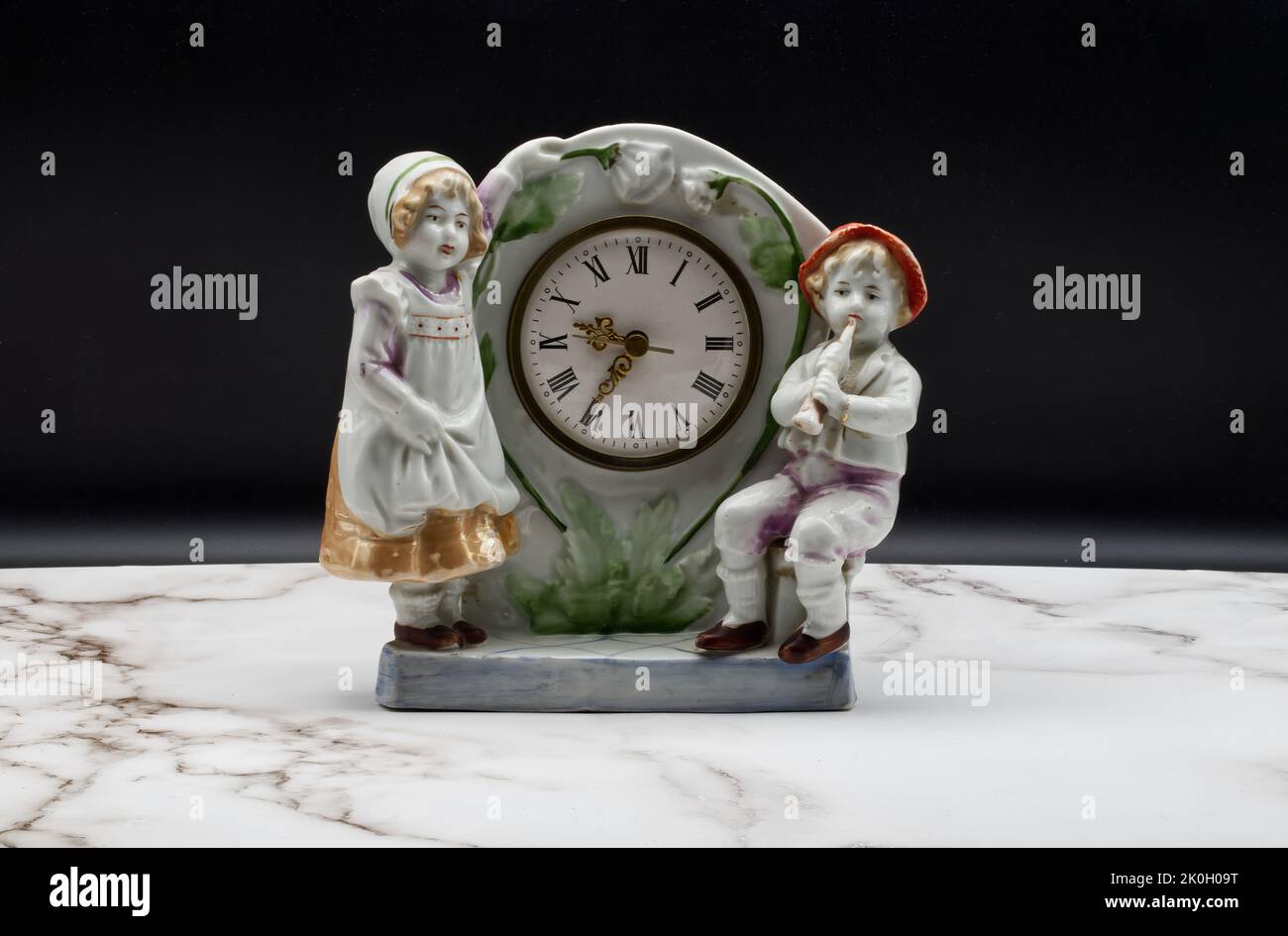 Vintage Italian ceramic table clock on marble table and black background. Stock Photo