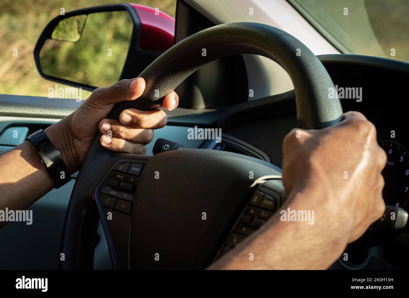 The hand is holding the steering wheel of the car Safe driving. Close-up Of A Man Hands Holding Steering Wheel While Driving Car Stock Photo