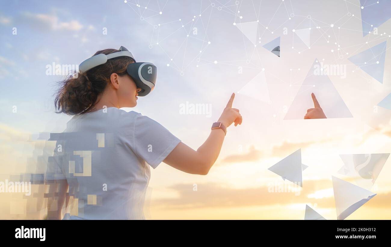 Metaverse technology concept. Woman with VR virtual reality goggles standing on nature. Futuristic lifestyle. Stock Photo
