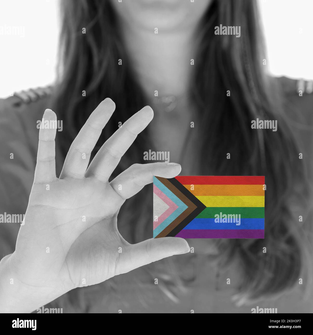 Businesswoman presenting a card with the Progress LGBTQ rainbow flag, selective focus Stock Photo