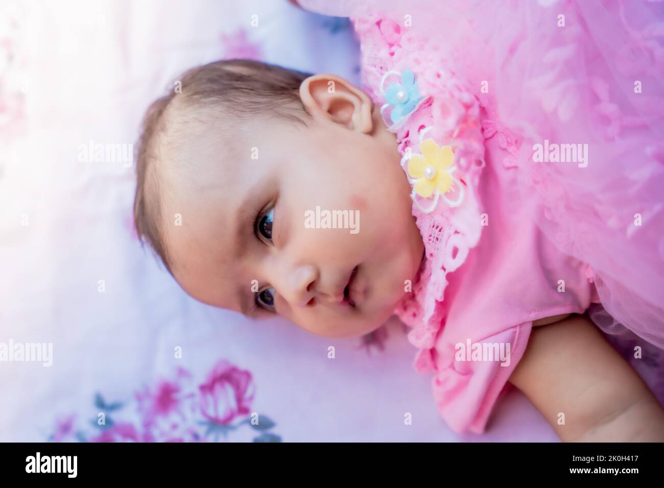 Cute baby girl lying down and looking in camera Stock Photo