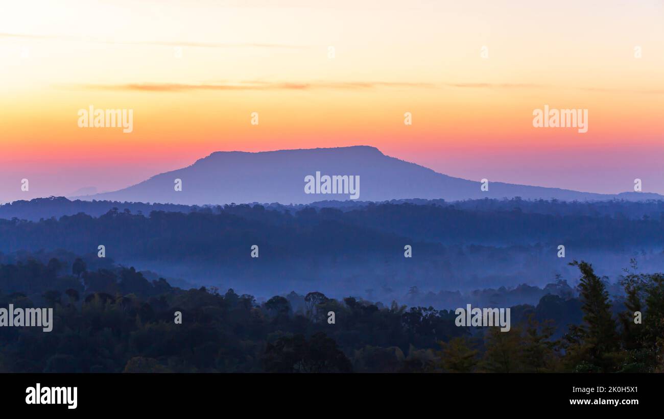 The scenery of blue mountains at dawn, fog covering pine forest, dramatic sunrise sky in the background. Nam Nao National Park, Thailand. Stock Photo