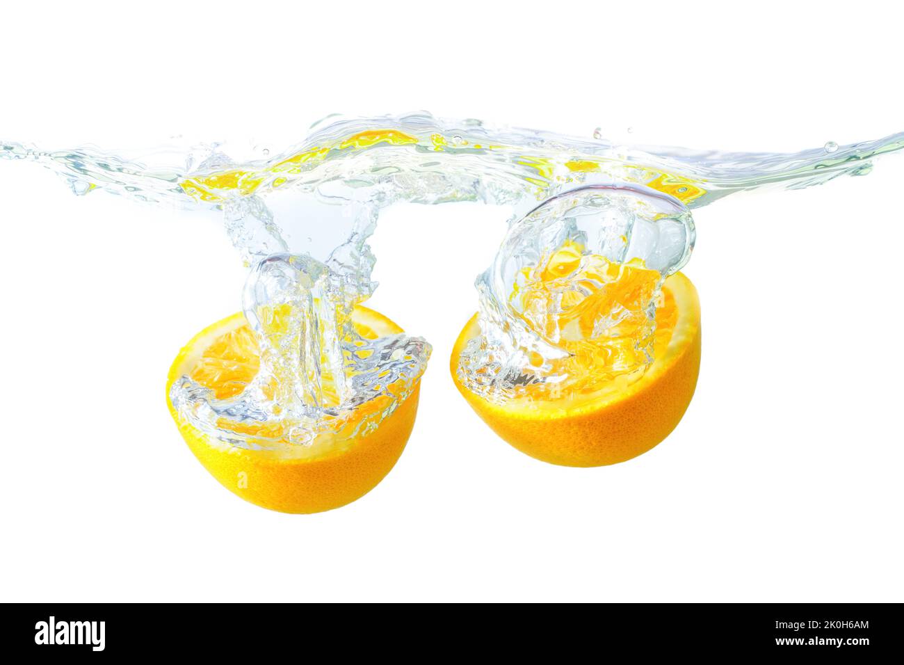 Orange halves cut wavy water surface with splashes and bubbles isolated on white background. Stock Photo