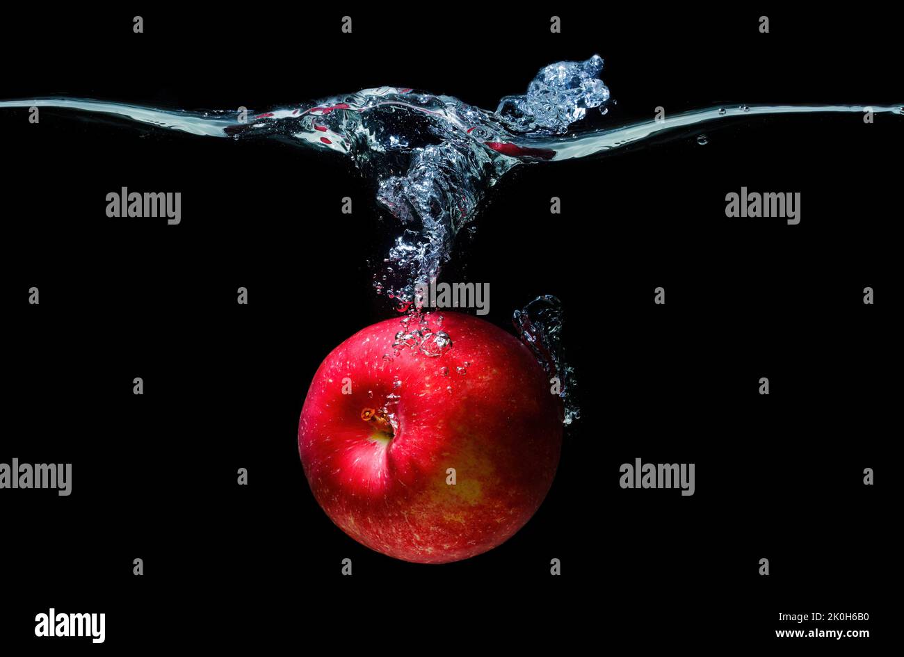 Fresh red apple dropped in water with splashes isolated on black background. Stock Photo