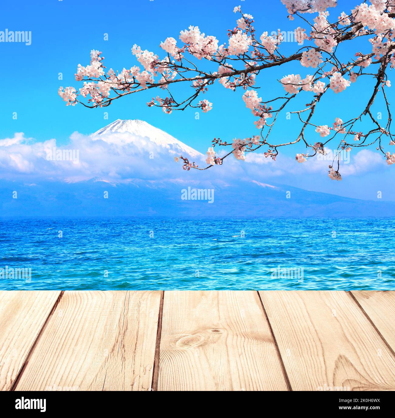 Sacred Mount Fuji, blooming sakura branch, lake and old wooden plank, Japan. Empty wooden table top and scenic with pond and Fujiyama volcano. Rustic Stock Photo