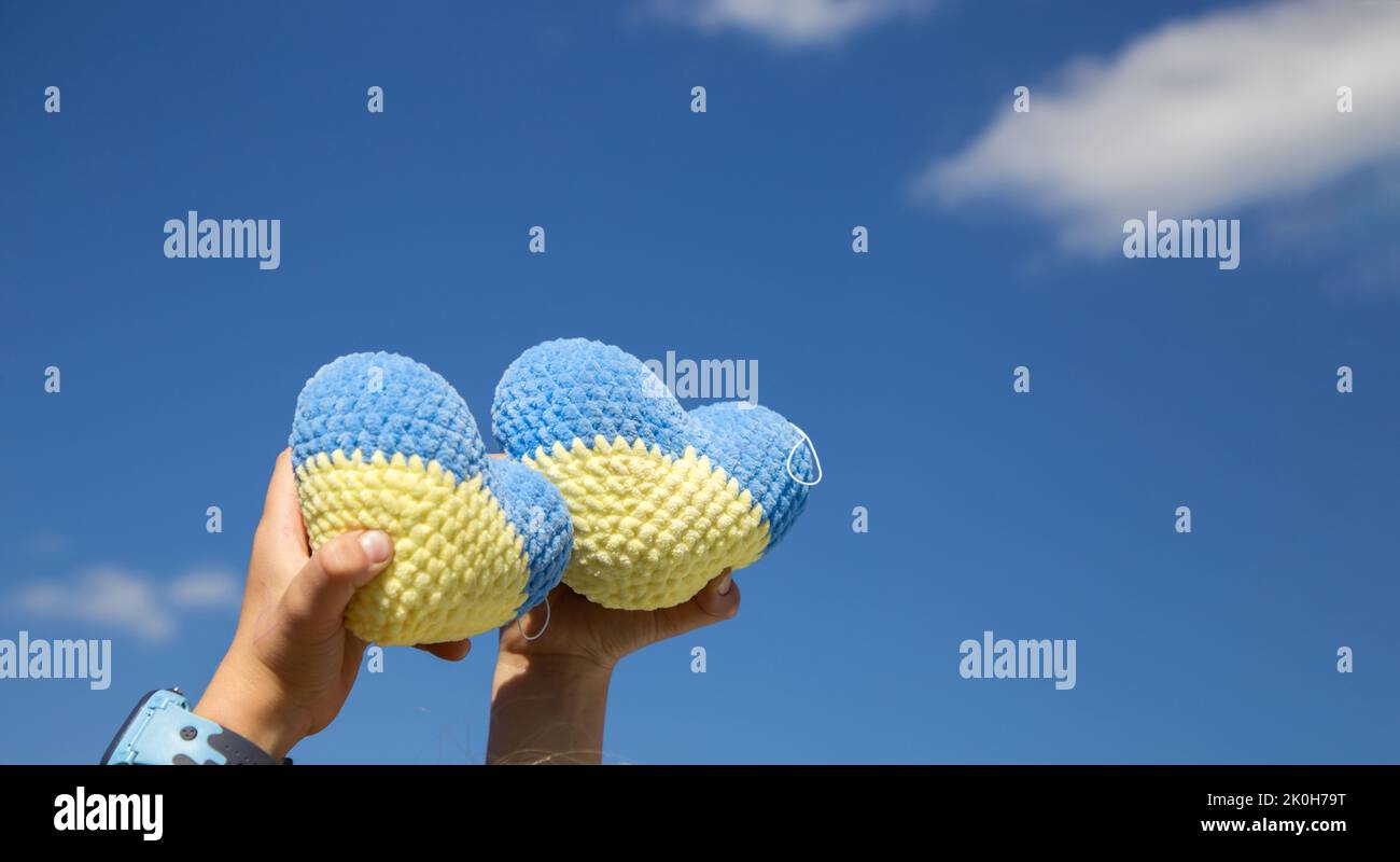 two knitted plush yellow-blue hearts against the blue sky. concept of patriotism, unity, support, peace for Ukraine. Proud to be Ukrainian. copy space Stock Photo