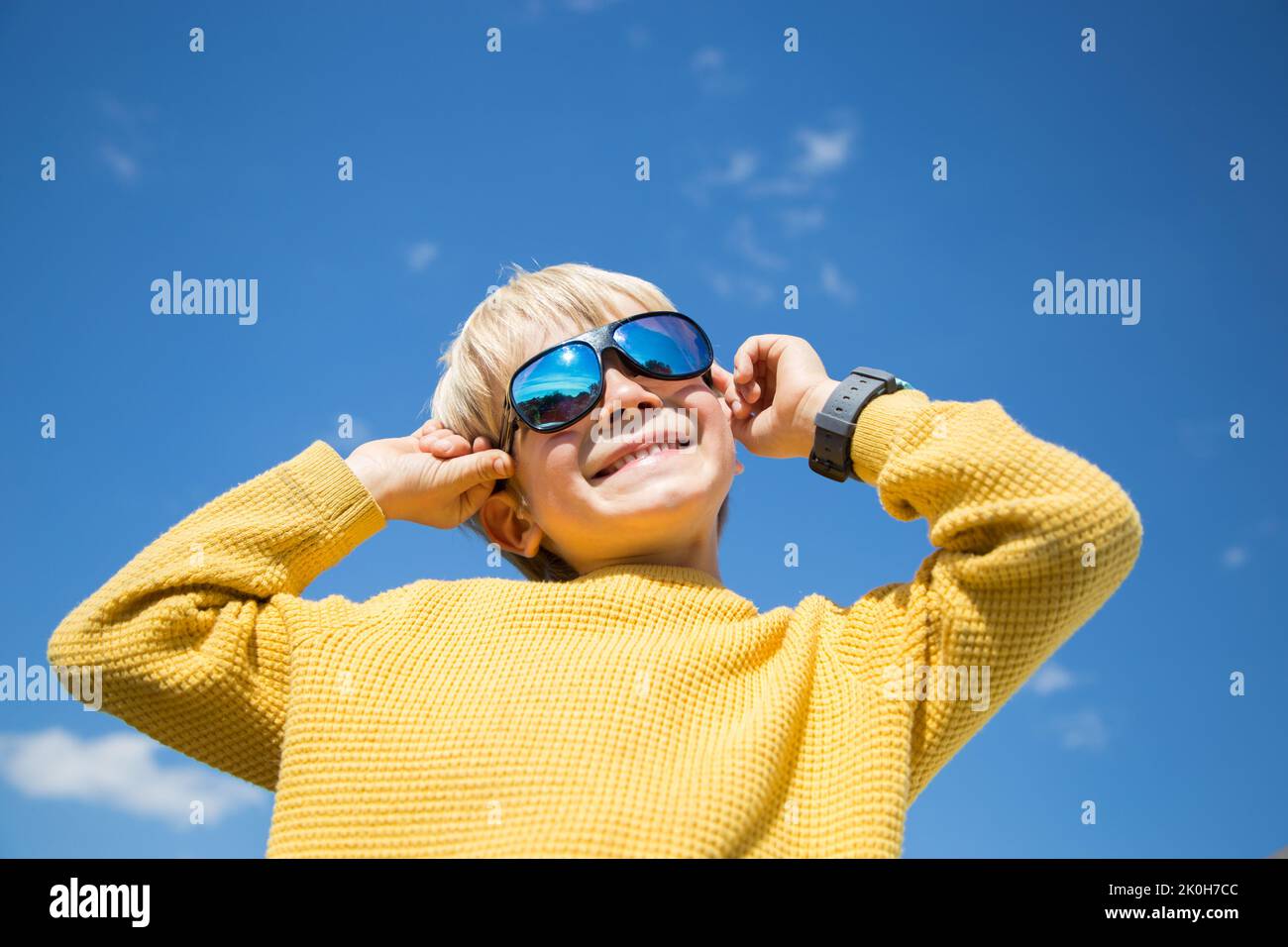 face of happy boy in sunglasses against sky. Color accent on yellow and blue colors of Ukrainian flag. Children of Ukraine for Peace. victory, joyful Stock Photo