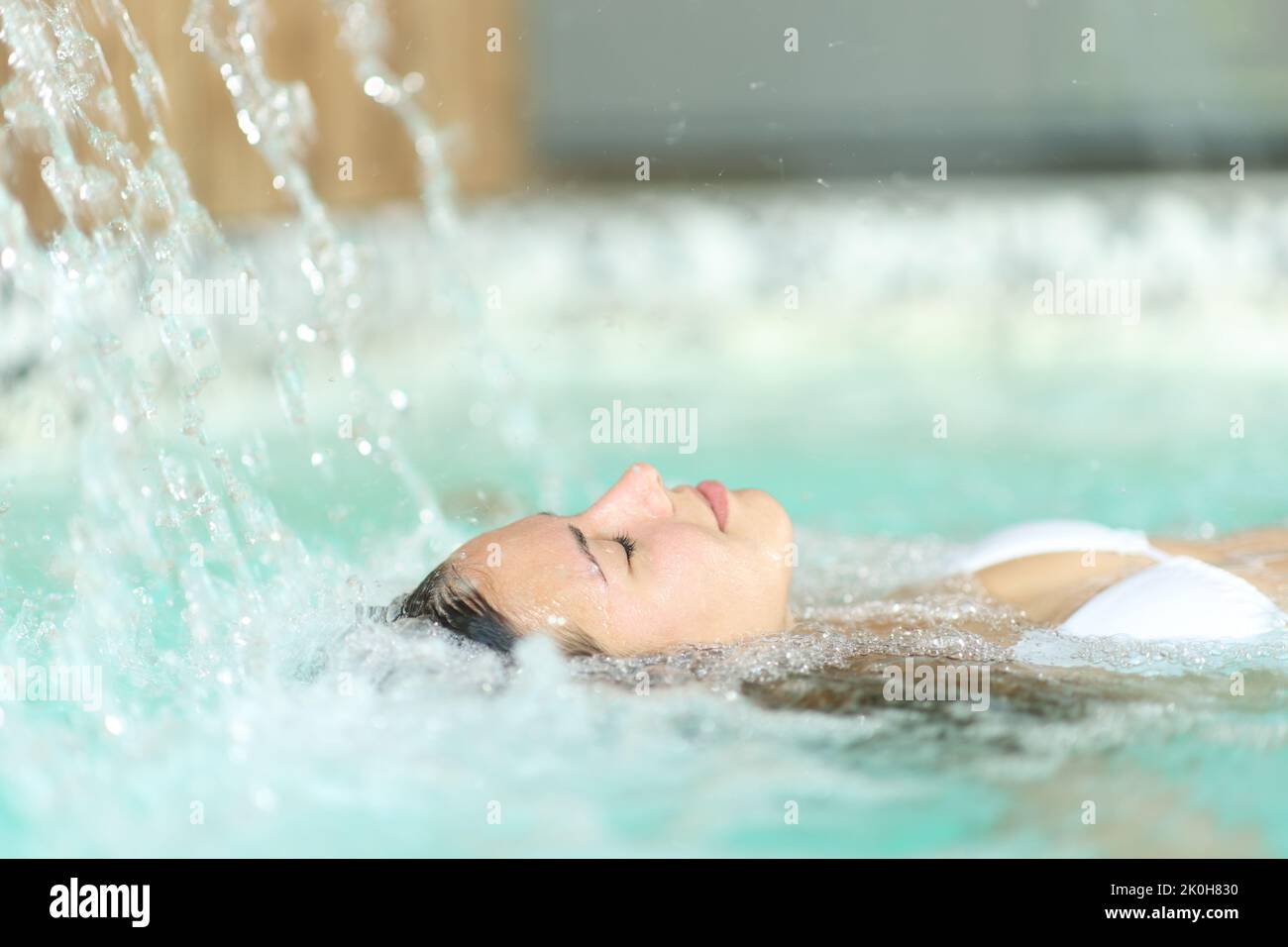 Side view portrait of a young woman in bikini relaxing floating in spa pool Stock Photo