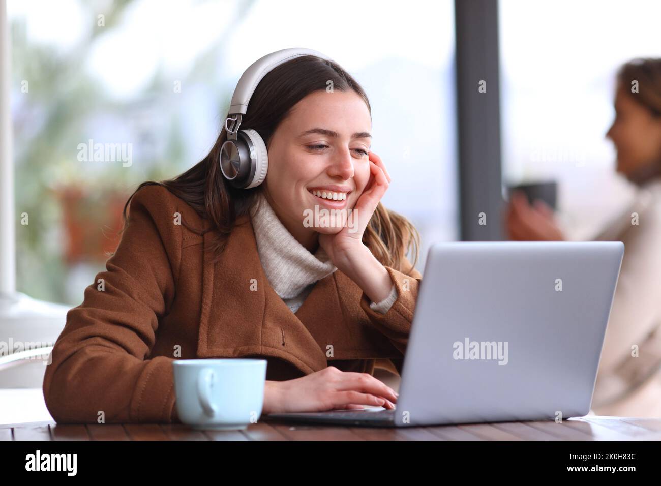 Happy woman in a bar watching media on laptop Stock Photo