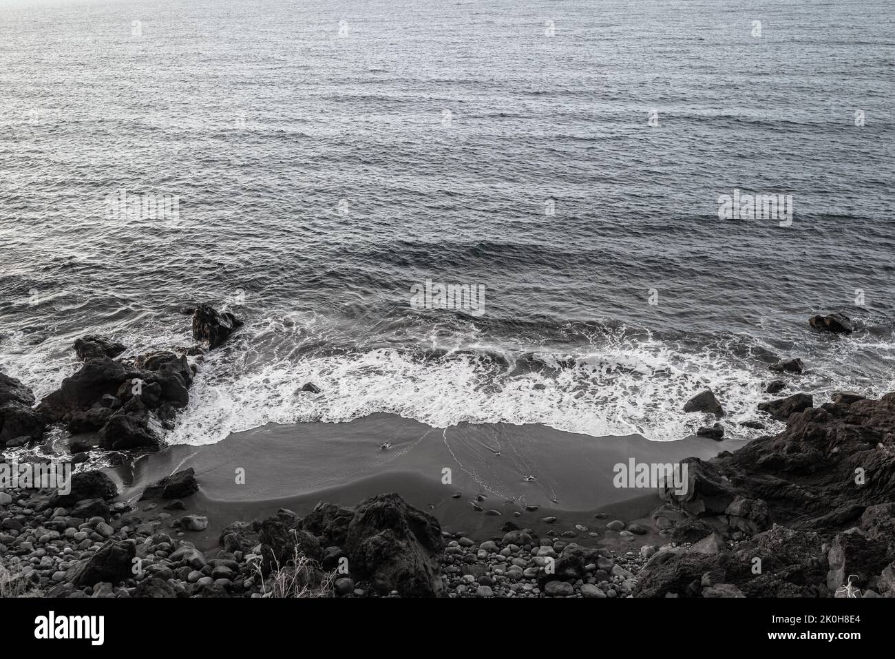 Black sand beach aerial view. Grey and black volcanic rocks and ocean waves Stock Photo