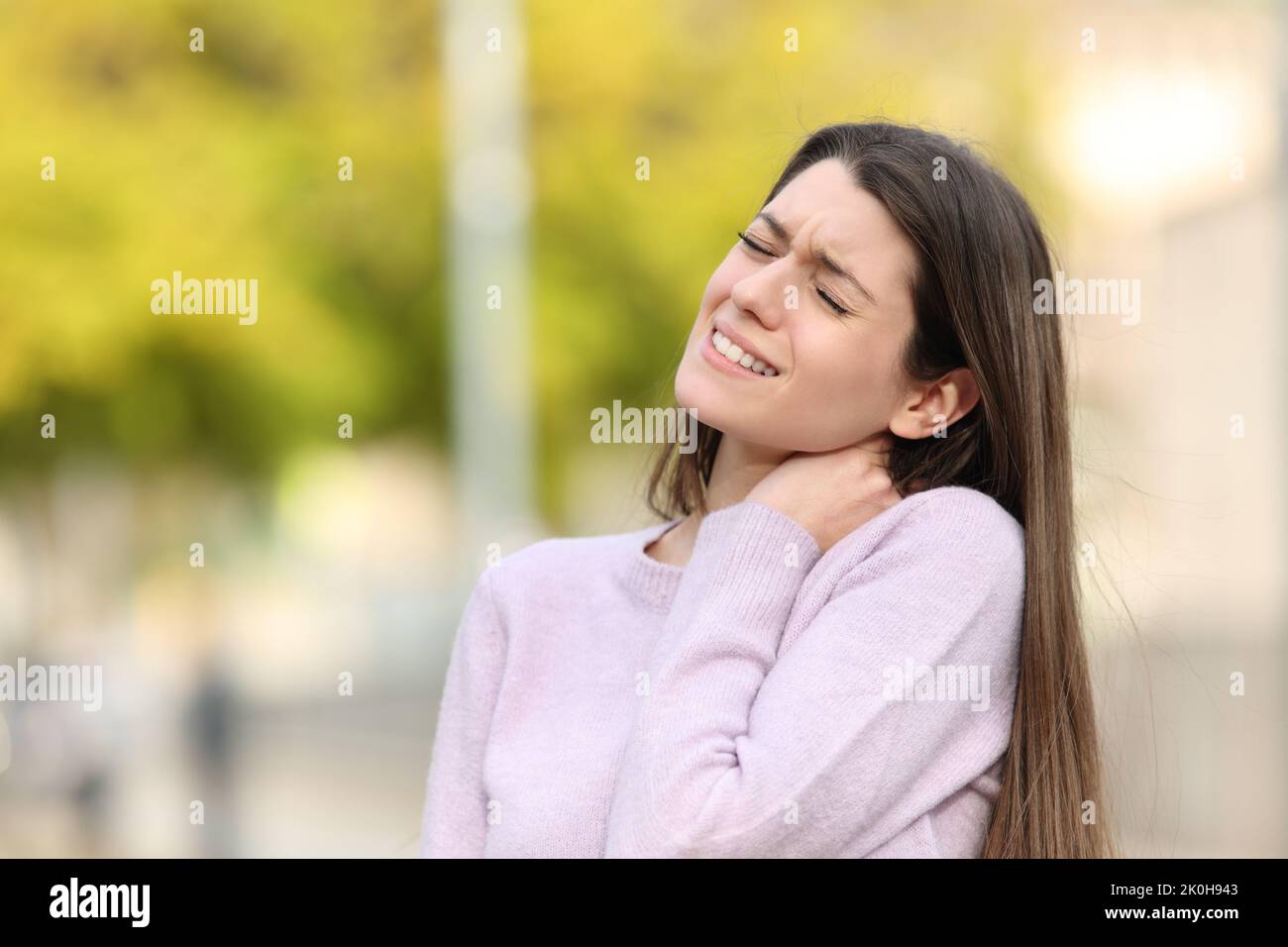 Teen complaining due neck ache standing in a park Stock Photo