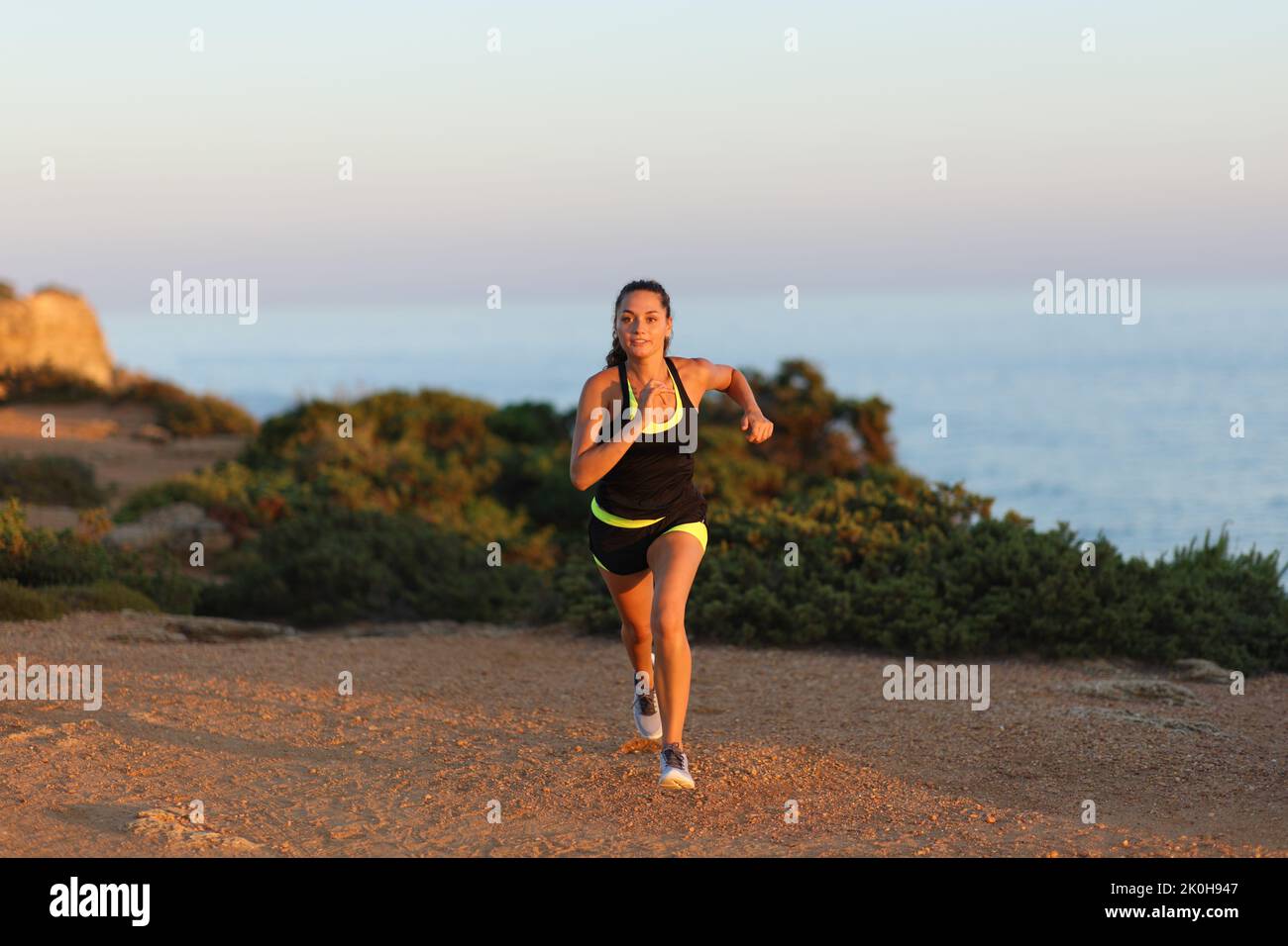 Front view portrait of a runner running at sunset on the beach Stock Photo