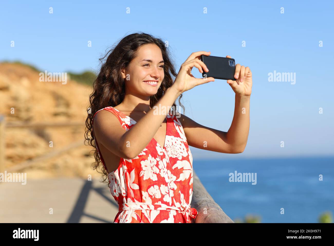Tourist on the beach taking photo with smart phone a sunny summer day on vacation Stock Photo