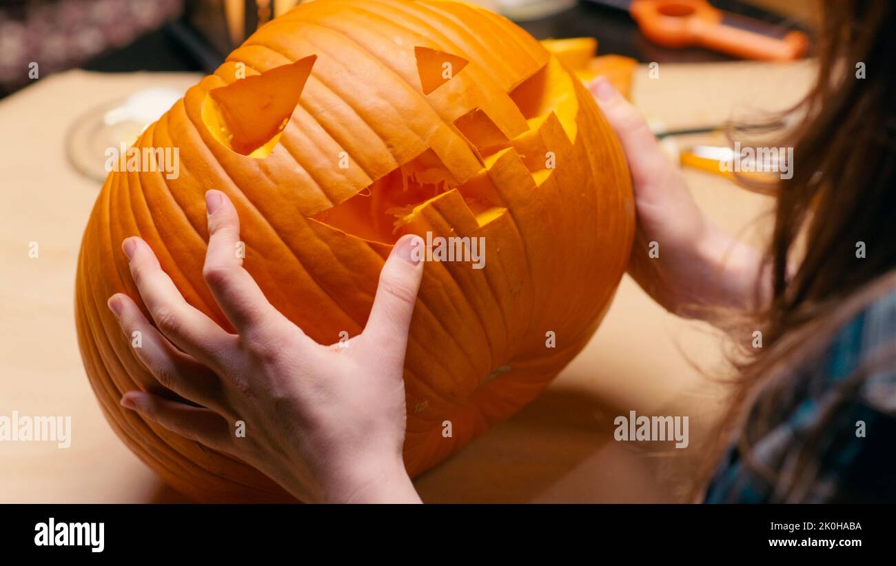 Preparing pumpkin for Halloween. Woman sitting and cleaning carved halloween Jack O Lantern pumpkin at home for her family. Stock Photo