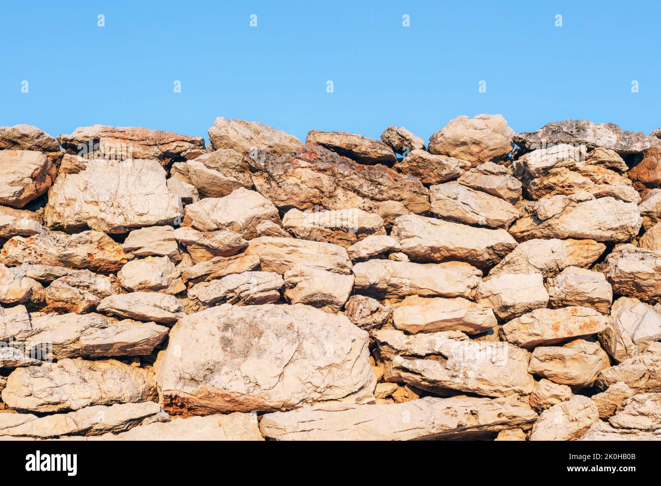 Old masonry stone wall and blue sky background, texture. Stock Photo