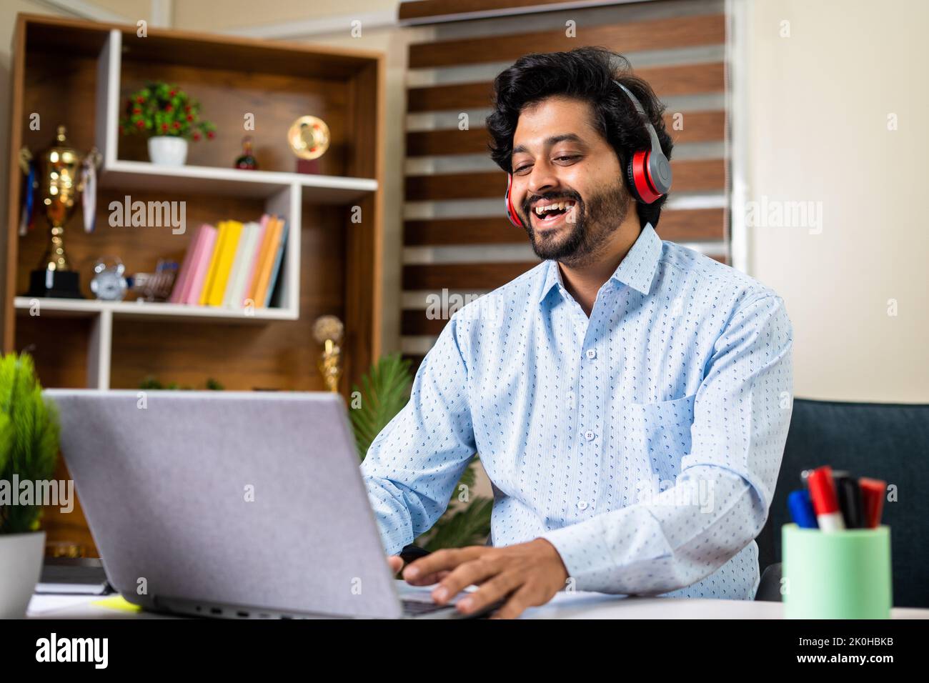 Happy businessman on online client meeting at office using laptop - concept of successful career, entrepreneur and executive. Stock Photo