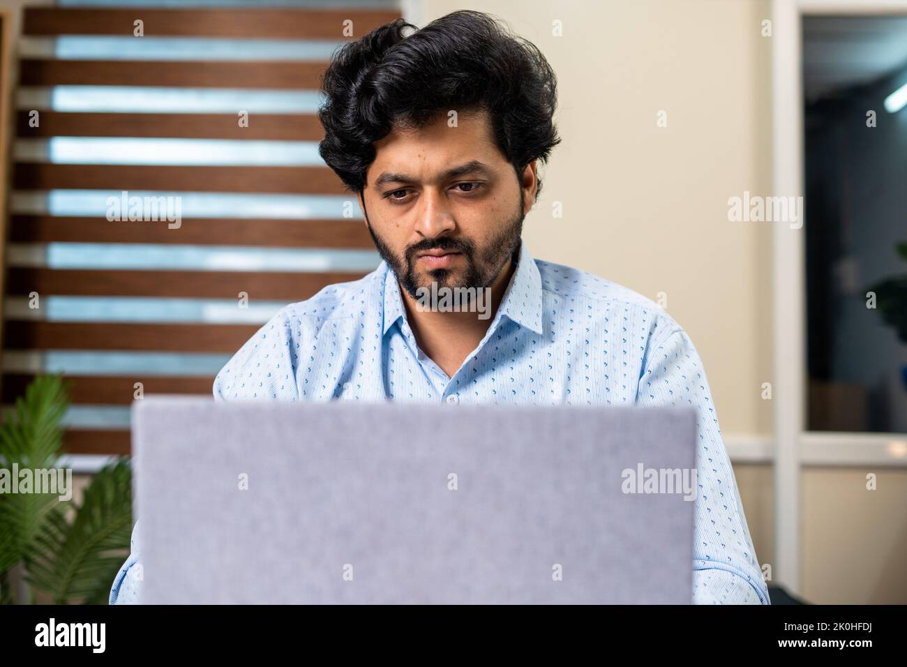 front view of corporate employee or entrepreneur seriously working on laptop at office - concept of focused, thoughtful and solving problem Stock Photo