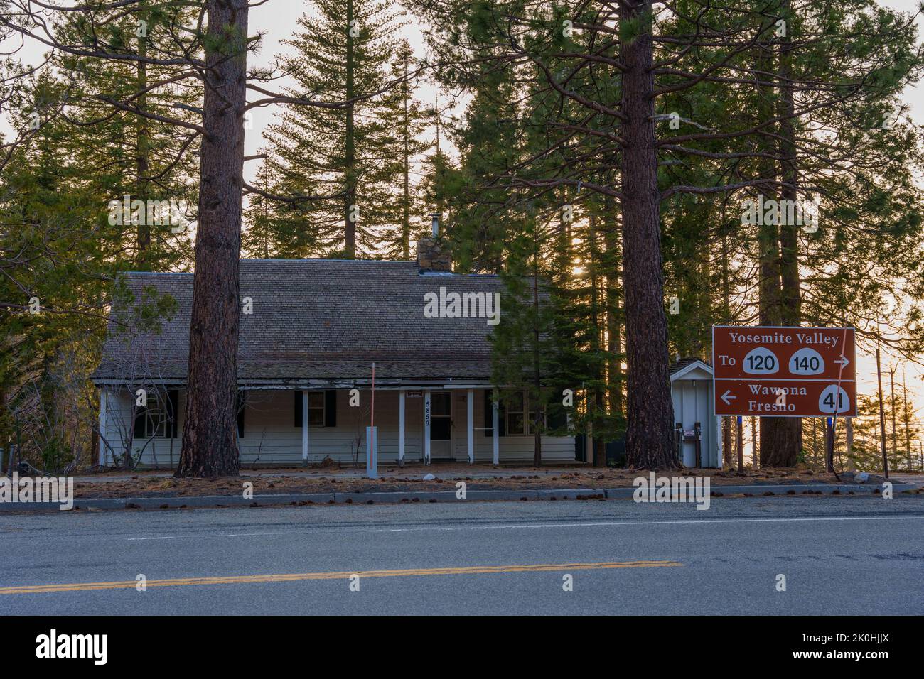 A cabin house by the road next to signage showing the directions to