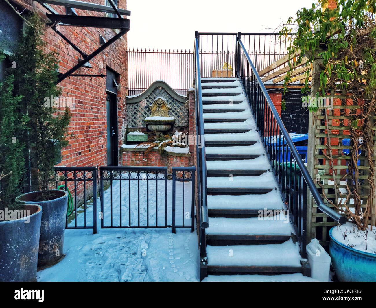 A metal stairway covered in snow in the backyard leading to house Stock Photo
