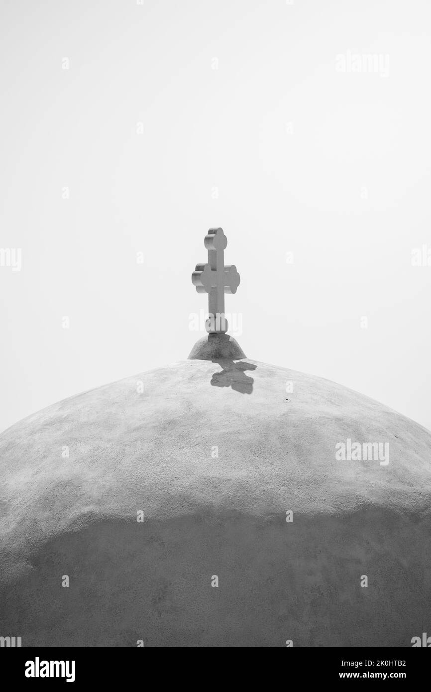 A vertical greyscale shot of a cross on the dome of a Greek Orthodox ...
