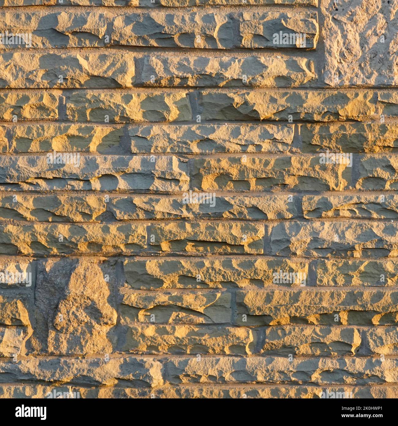 Sunshine on natural York stone blocks cut & dressed from redundant London paving slabs reused in external skin of house cavity wall Essex England UK Stock Photo