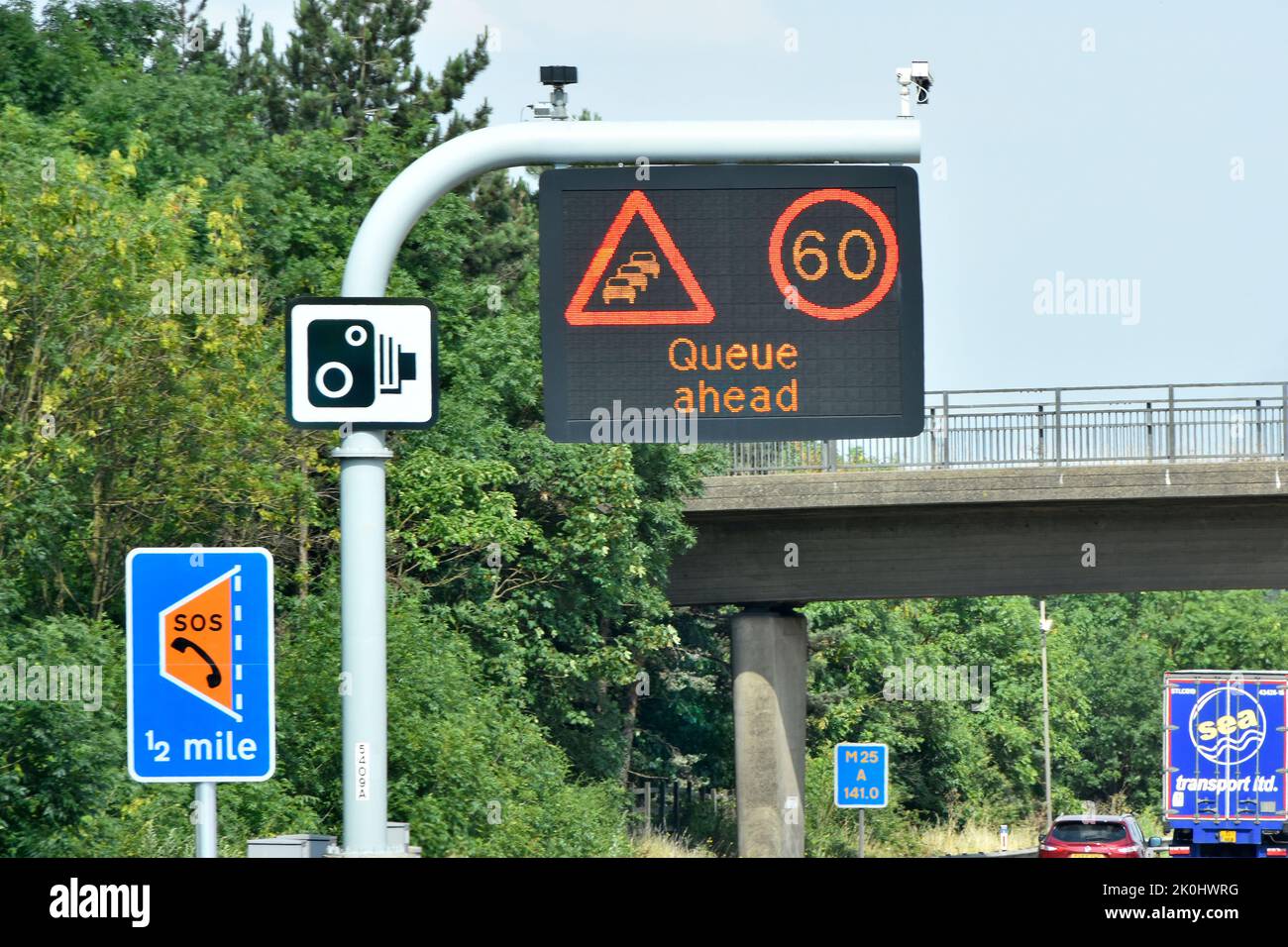 Single panel M25 motorway sign above lane one 60MPH variable speed limit & Queue Ahead message & smart lane layby half mile & standard camera signs UK Stock Photo