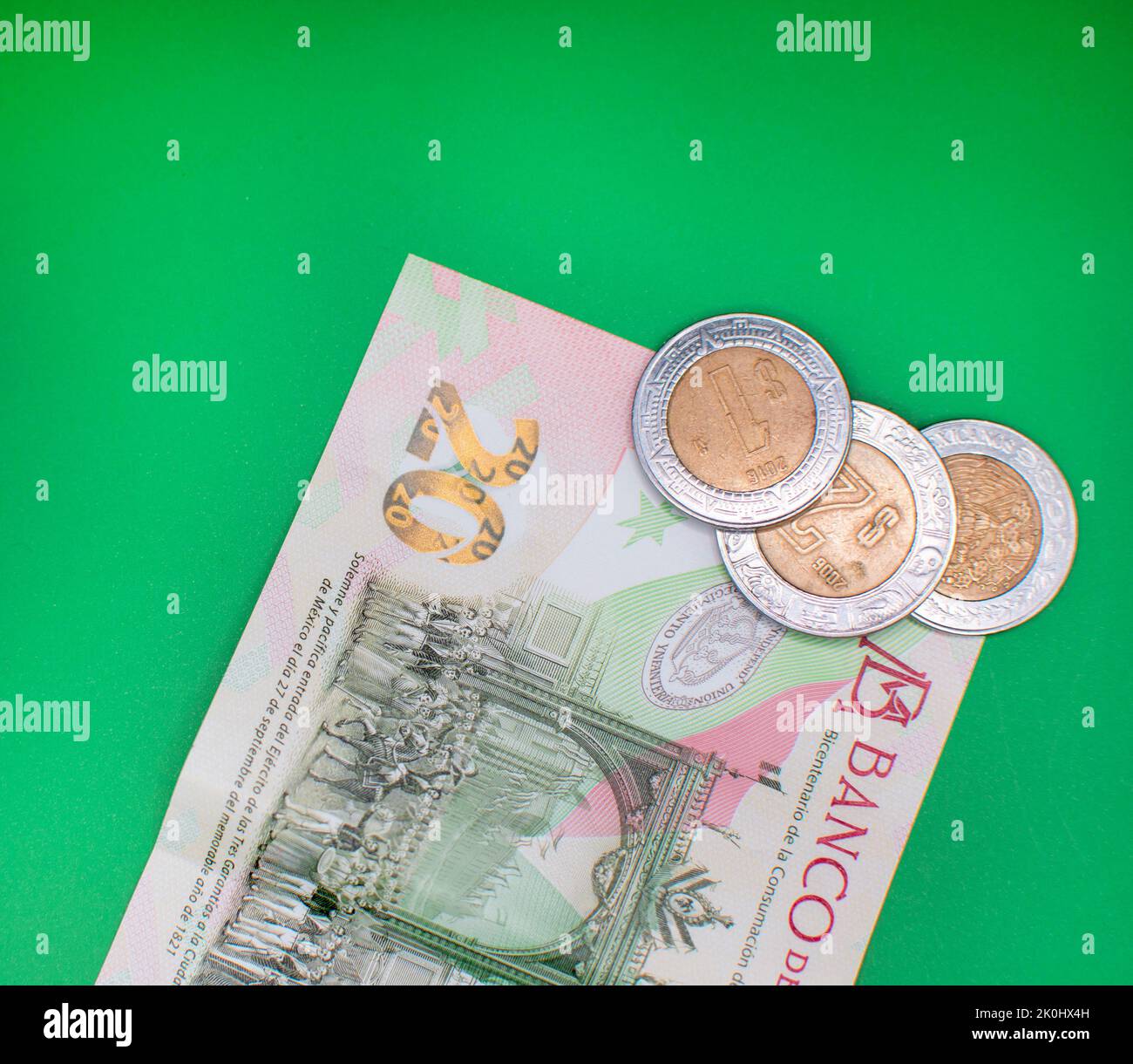 A top view of 20 Mexican peso banknote with coins on a green background Stock Photo
