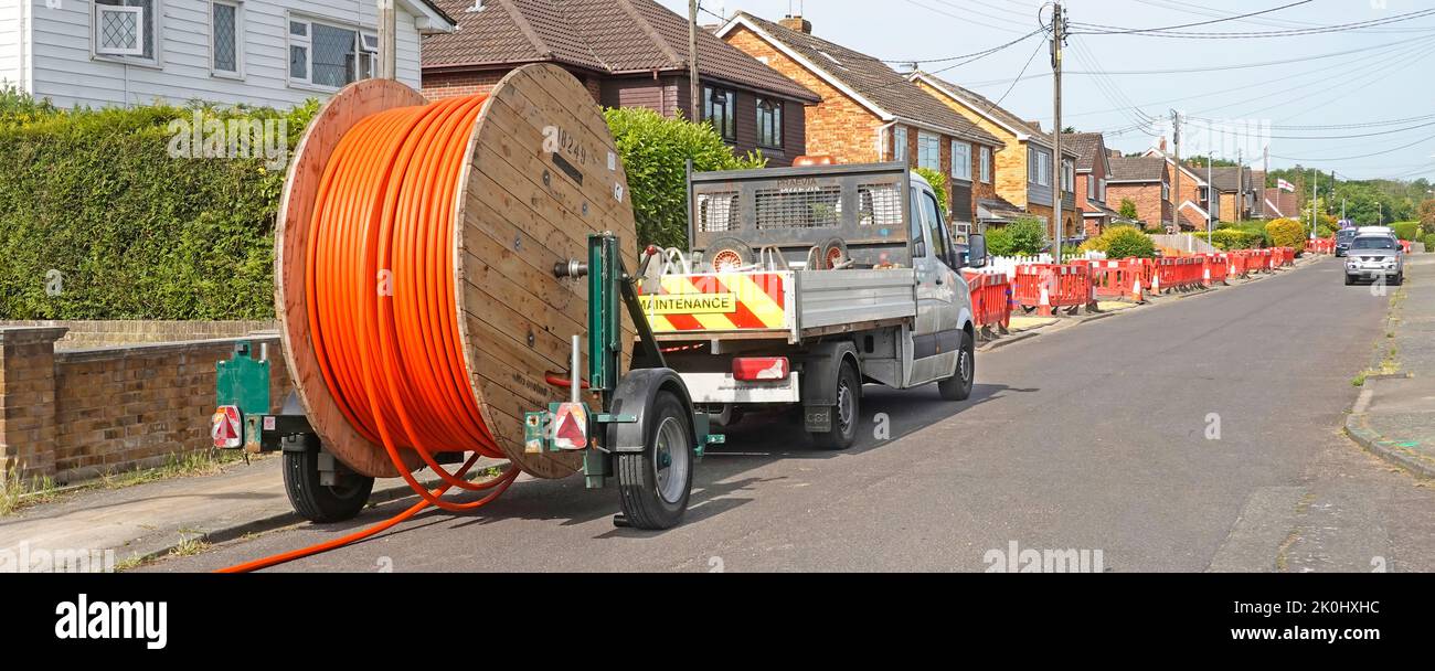 Fibre optics super fast broadband infrastructure large cable drum & lorry tow truck residential street pavement trench works crossover closed Essex UK Stock Photo